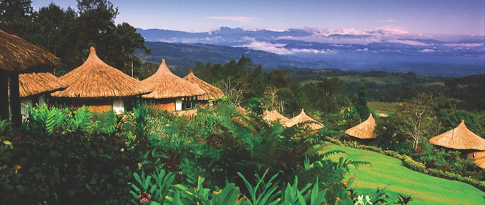 Thatched highland lodge huts overlooking misty mountain valleys.